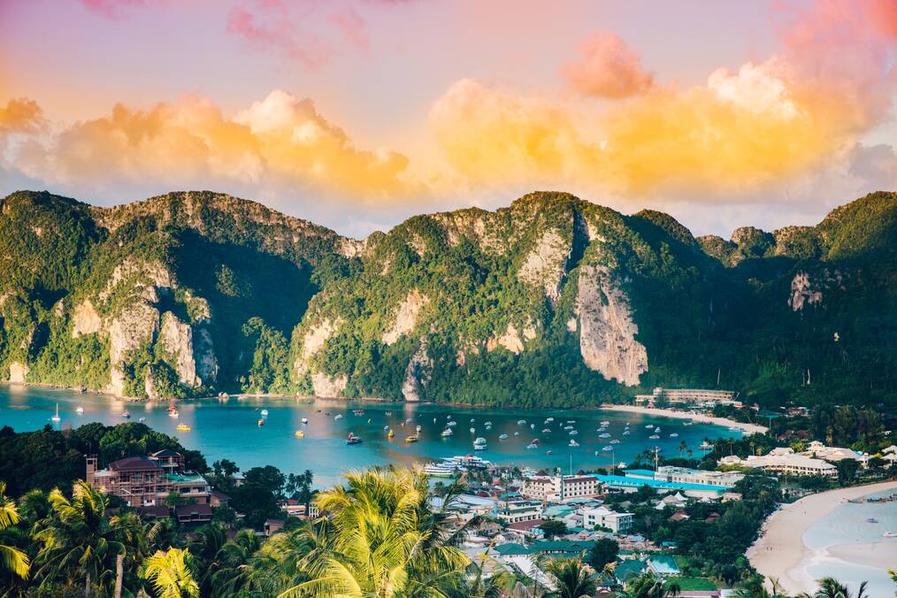 A yellow, pink, and orange sunset over a bay with high mountains in Thailand