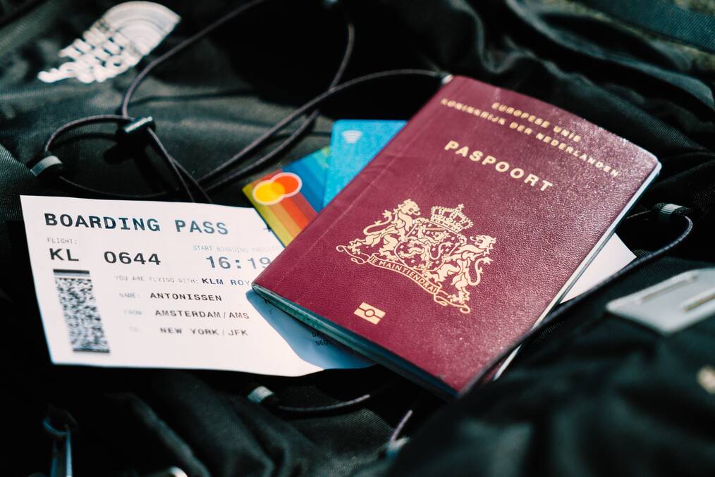 A passport and boarding pass sit on a backpack.