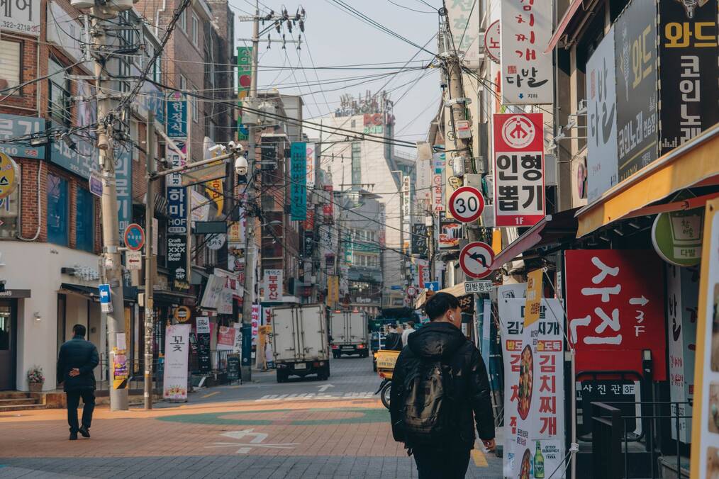 People walk down a commercial street in Korea.