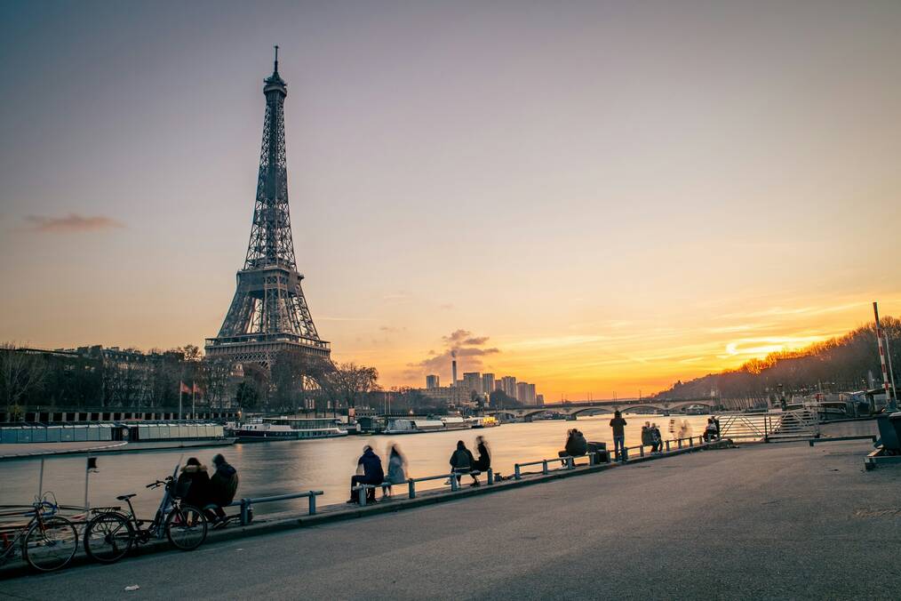 People relaxing near the river beside the Eiffel Tower