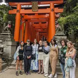 group smiling in front or red gate