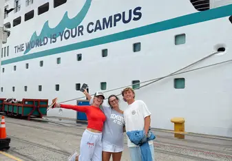 Semester at Sea students smiling in front of docked cruise ship