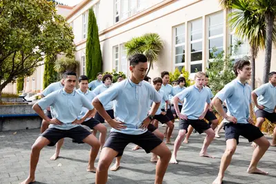 Group of students outside in uniform performing haka