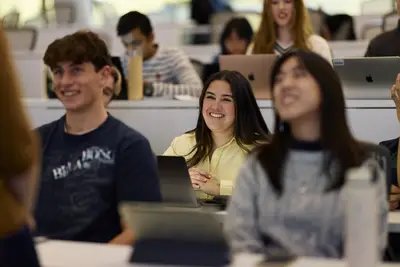 Students smiling with laptops in class