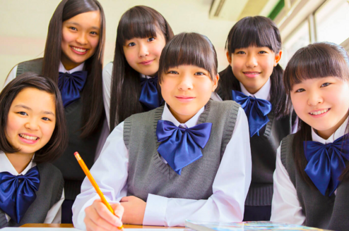 group of students wearing school uniforms with blue bows