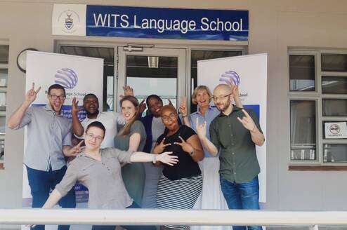Group of teachers standing in front of a Wits Language School sign