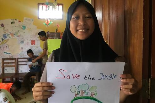 Student holding a 'Save the Jungle' Poster