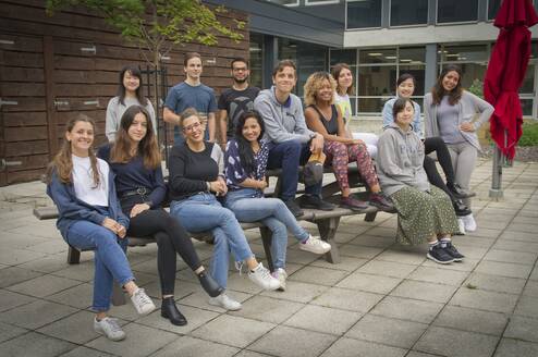 Previous summer school students sitting on a bench outside the building