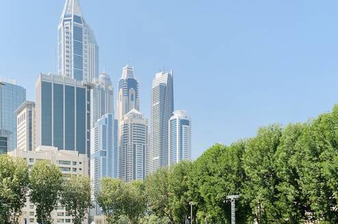 Students on the green AUD campus with the Dubai skyline in the background.