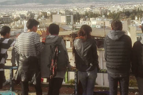A group of students lined up a long a fence look at the view before them in Athens, Greece