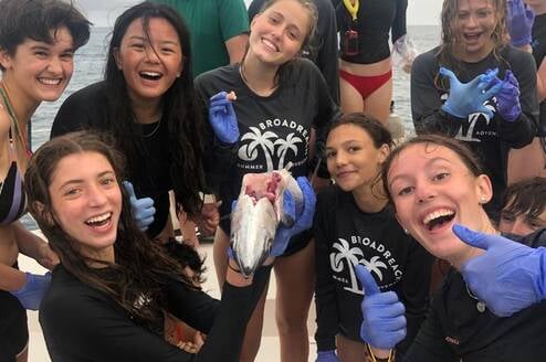 Group of teens on boat dissect fish