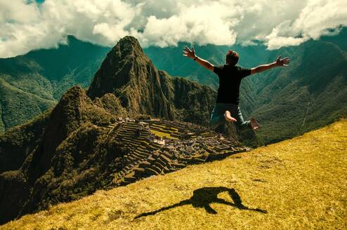 A man jumps in the air near Machu Picchu