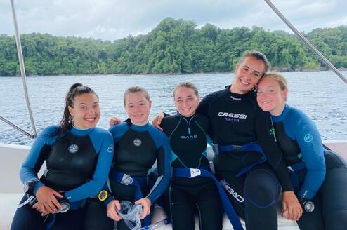 a group of divers smile on a boat