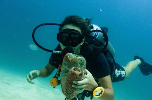 a scuba diver holds trash 