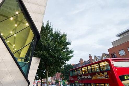 Red London bus driving past London Met grad center