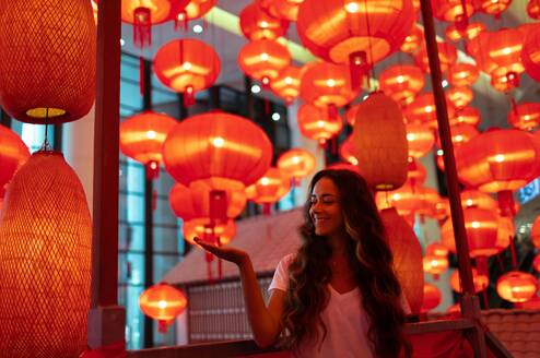 A woman stands in a room full of red lanterns.
