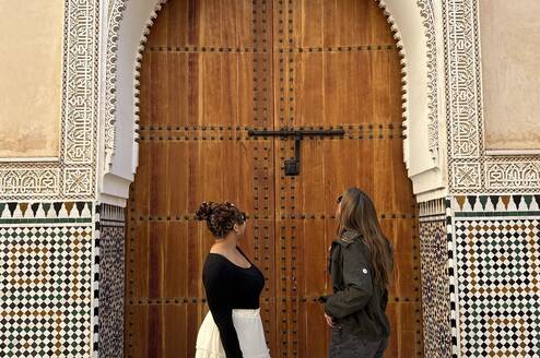 Two students standing in front of a wooden, carved door in the Medina
