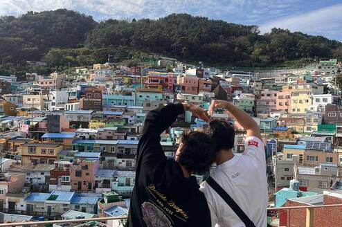 Students making heart hands over Busan skyline