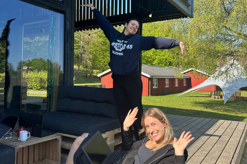 Two interns working outside on bean bags on a porch