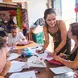 A teacher works with a group of adults at a table.
