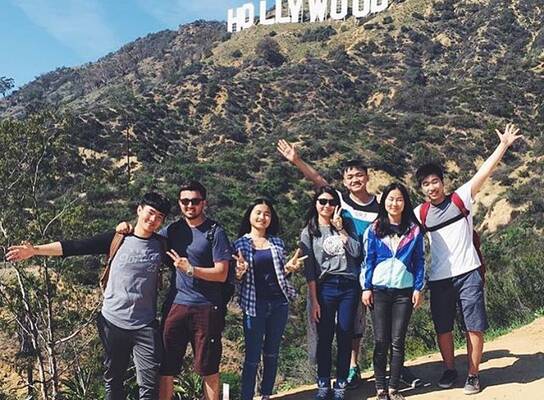 People posing in front of Hollywood sign