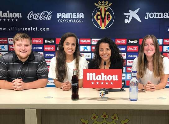 Marketing interns sit at a table with logos behind them