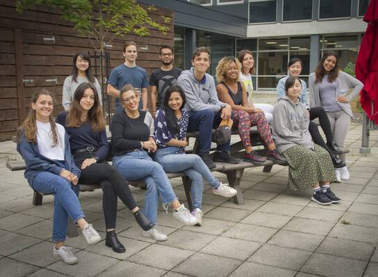Previous summer school students sitting on a bench outside the building