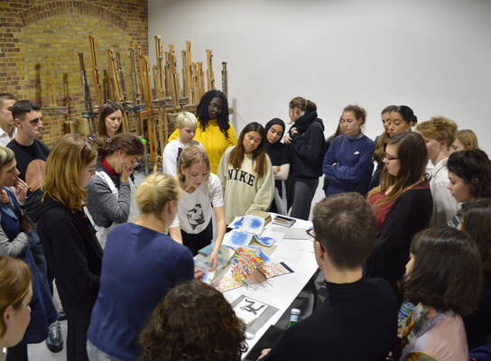 Group of young students gathered around a painting