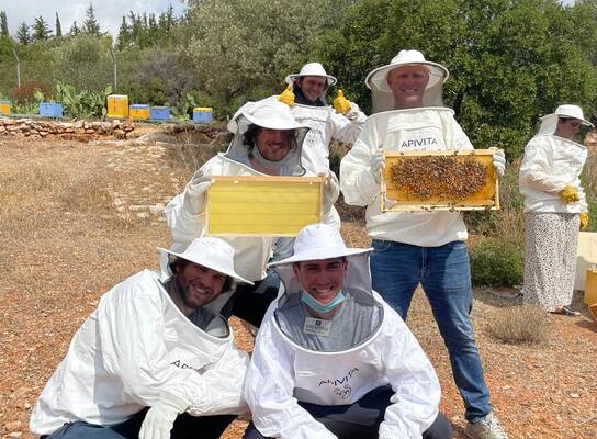 students in protective clothing showing off beekeeping