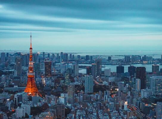 Panorama image a metropolis skyline with numerous high rises visible dwarfed by a tall red and white tower
