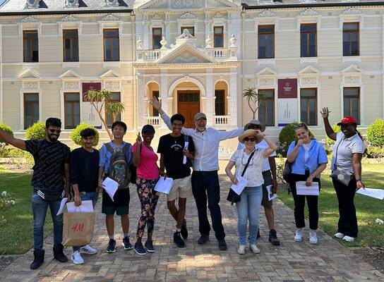 Group of diverse male and female students standing in front of university building