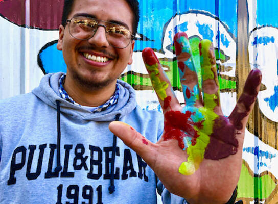 A student holding up a hand with paint on it 