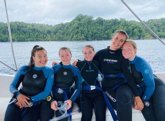 a group of divers smile on a boat