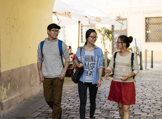 Three students walk on the street.
