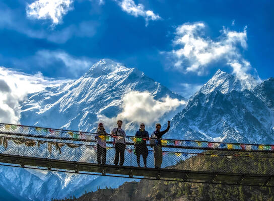 Students pose on bridge in Himalayas.