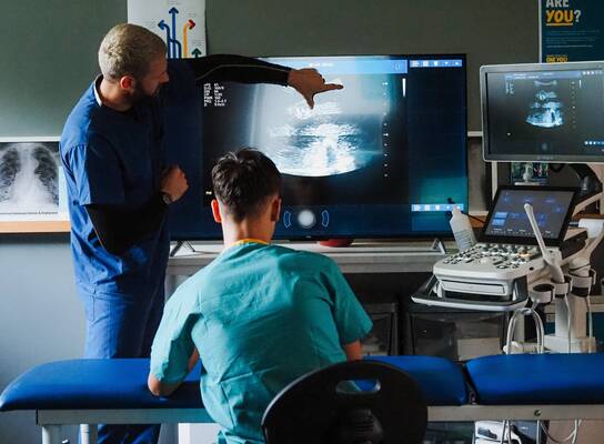 Doctor teaching ultrasound imaging to students during a hands-on clinical skills summer programme in Liverpool