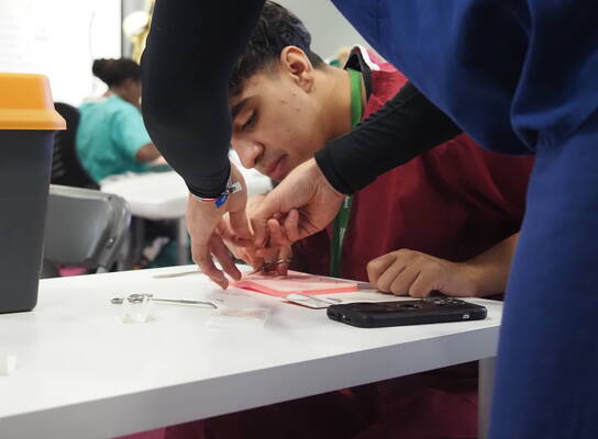 Student practising suturing techniques during a hands-on emergency medicine summer school in Liverpool
