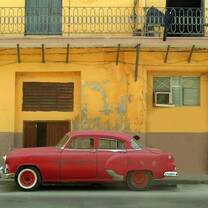antique red car in front of yellow building