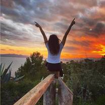 girl with hands up at sunset on a hike