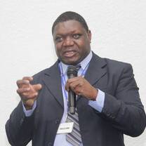 a gentlemen  wearing a coat and tie while taking his speech 