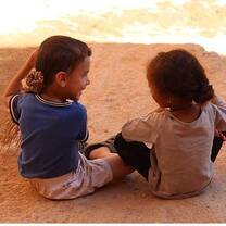 Two kids sitting on the sand