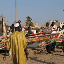 Men standing by their boats on a beach. 