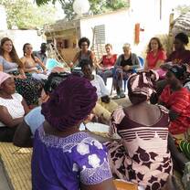 Gathering of people in a circle in traditional clothing smiling. 