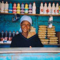 Woman standing behind the bar at a coffee shop smiling. 