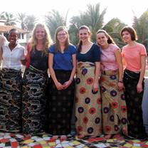 Students and faculty wearing traditional skirts smiling together. 