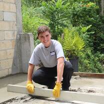 A male volunteer learning to lay a cement floor with Global Works!