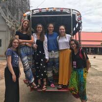 Team members are standing on the back of a truck and smiling in one of the famous local markets in Thailand. 