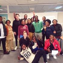 15 Students standing in front of a white board looking happy