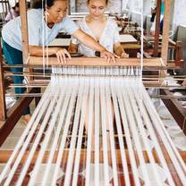 Pacific Discovery student being taught to weave fabric by local on loom