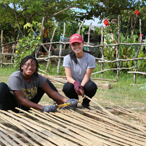 2 Pacific Discovery students posing for camera with bamboo wood
